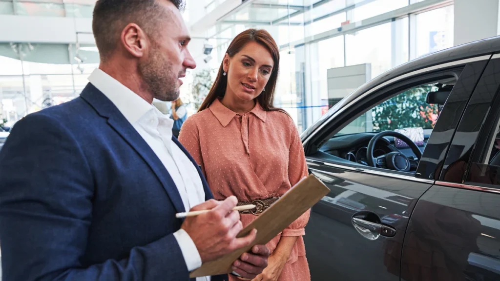 A service advisor with a clipboard explaining the differences between an extended warranty and a vehicle service contract to a car owner.
