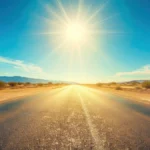 Blazing sun over empty desert highway. Keep your car cooler with these tips.