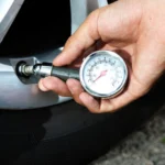 A tire pressure gauge being used for monthly car maintenance