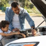100K mile car maintenance: a child and adult checking under the hood of a car with the hood raised