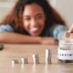 vehicle service protection saves money: a smiling woman adding a coin to a jar labeled Savings beside rising stacks of coins