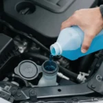 Person checking engine oil dipstick under the hood of a car to check car fluids